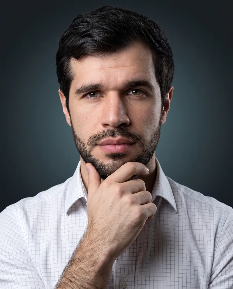 Retrato do Dr. José Ricardo Ristow em fundo escuro, com a mão no queixo e o olhar atento