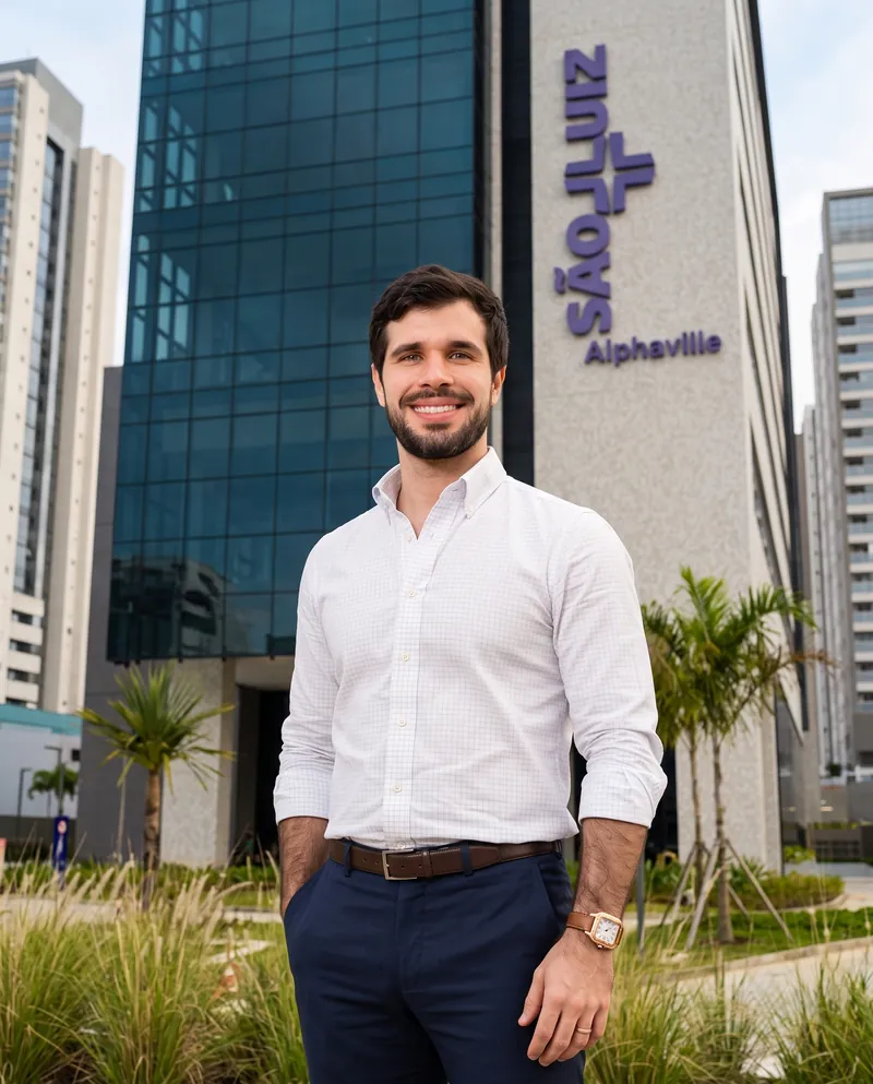 Dr. José Ricardo Ristow sorrindo em frente à fachada do Hospital São Luiz Alphaville, com o letreiro do hospital ao fundo